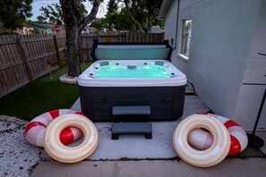 Un jacuzzi con dos anillos inflables, una valla de madera y una casa al fondo.