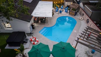 Un patio trasero con piscina, mobiliario exterior y un porche cubierto.