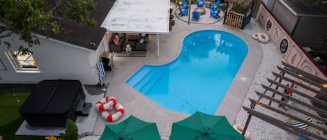Ein Garten mit Schwimmbad, Gartenmöbeln und einer überdachten Terrasse.