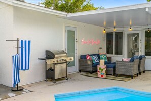 A poolside area with a grill, lounge chairs, and a neon sign. - Resort Style Backyard Tiki Bar Renovated Pool (Largo)