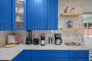 Una cocina con gabinetes azules, una cafetera, un tostador y un bol de fruta.
