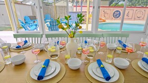 A dining table set for a meal with a view of a swimming pool and a backyard. - Resort Style Backyard Tiki Bar Renovated Pool (Largo)