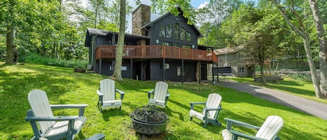 Een lodge met een stenen open haard, buiten zitplaatsen en een terras met uitzicht op een bebost gebied.