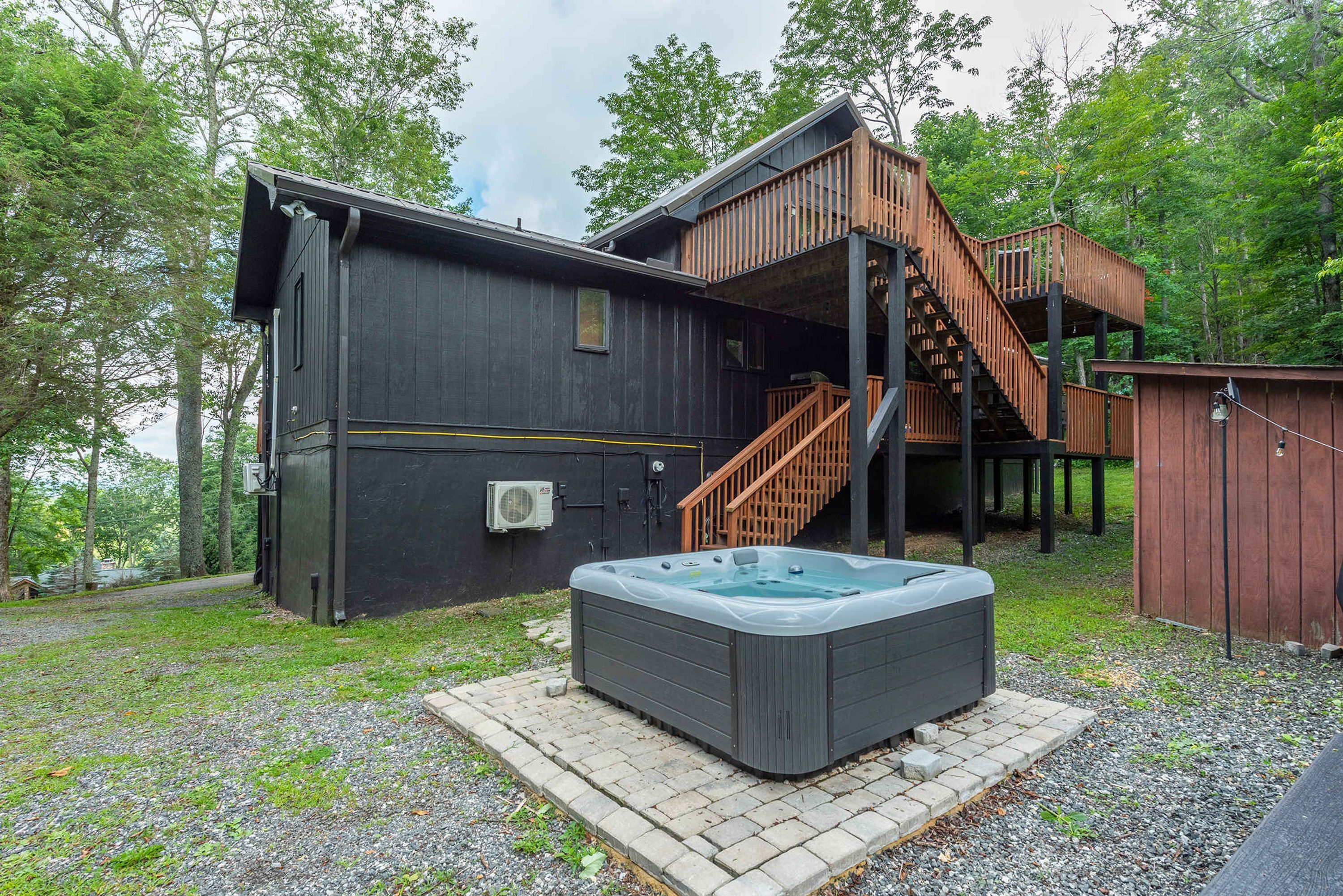 En hytte med jacuzzi, træterrasse og en trappe til øvre plan.