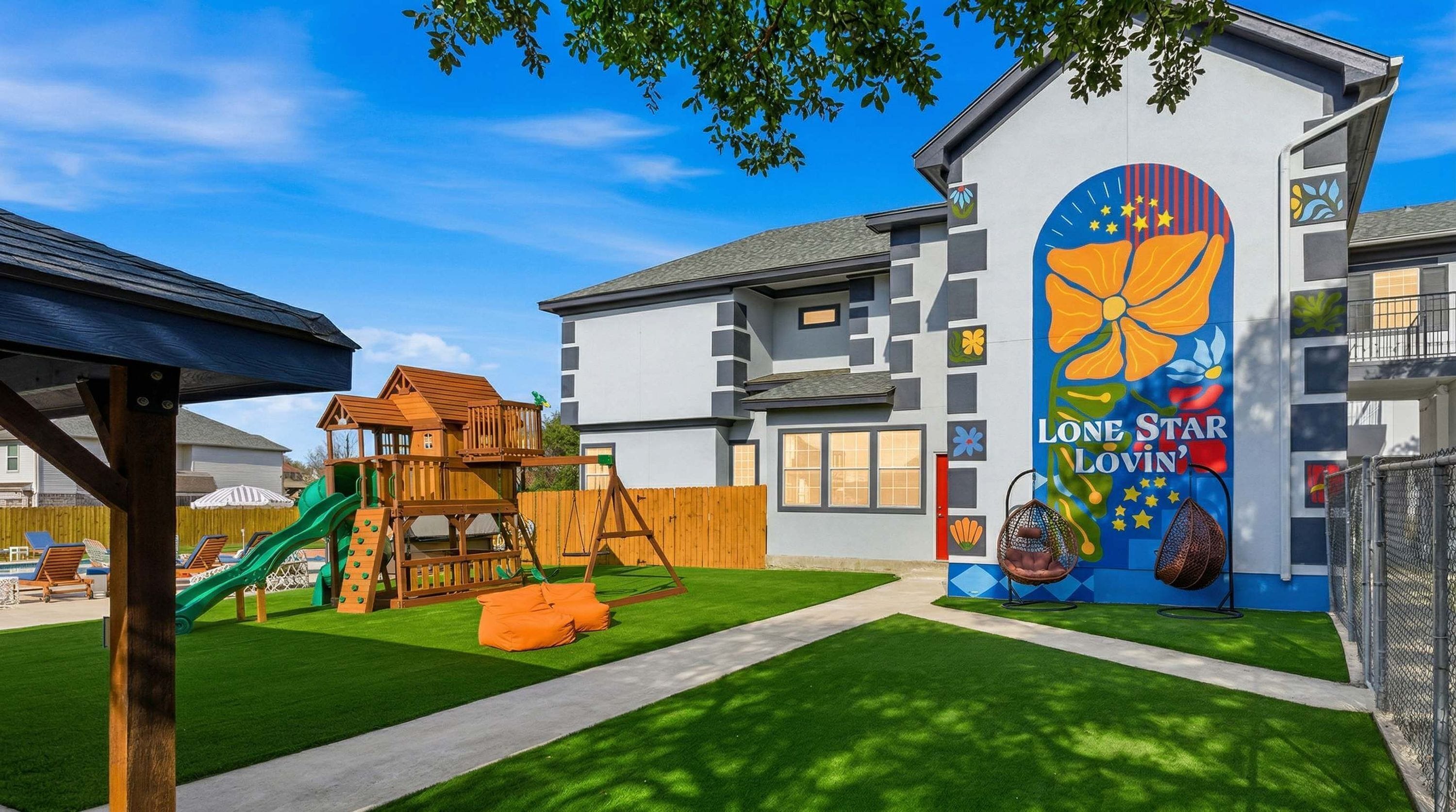 A residential building with a children's play area, a swimming pool, and a mural on the exterior wall.