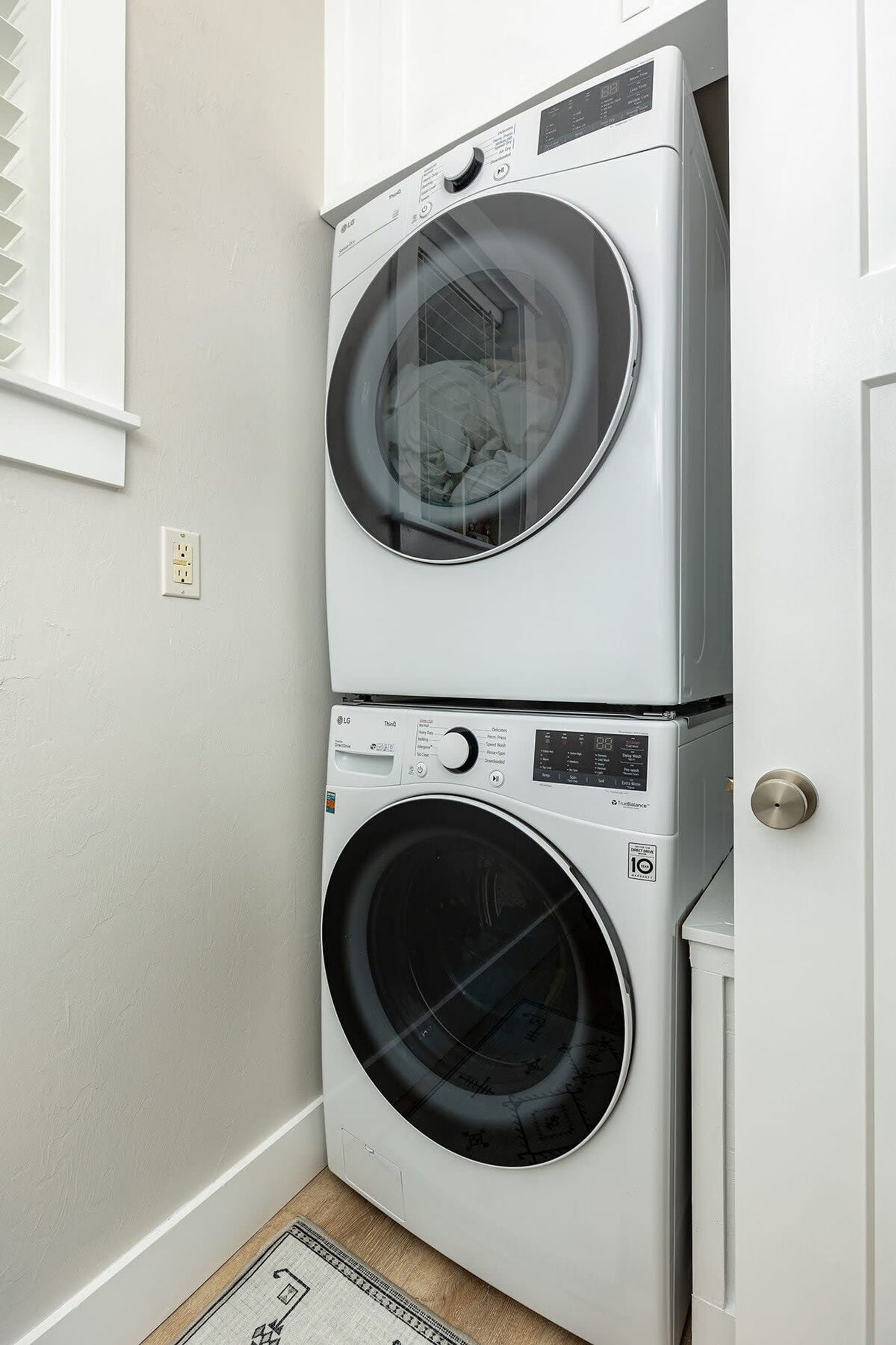 A stacked washer and dryer unit in a laundry room with a door and a window.