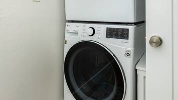 A stacked washer and dryer unit in a laundry room with a door and a window.