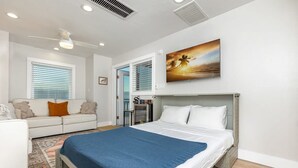 A modern bedroom with a large bed, a sofa, and a painting. - 3 Story Haven Fire Pit Kayaks Updated 360 Views (Cedar Key)