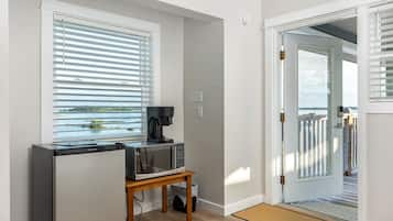 Cocina compacta con refrigerador, microondas y cafetera sobre una mesa de madera.