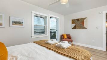 A bedroom with a bed, a window, a ceiling fan, and a painting on the wall.