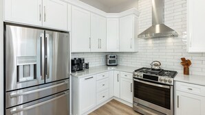 A modern kitchen with white cabinetry, stainless steel appliances, and a built-in oven. - 3 Story Haven Fire Pit Kayaks Updated 360 Views (Cedar Key)