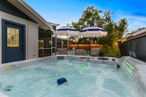 Ein Whirlpool mit Warnhinweis, umgeben von Gartenmöbeln und Sonnenschirmen.