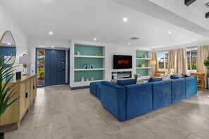 Uma sala de estar moderna com um sofá azul, televisão de tela plana e lareira.