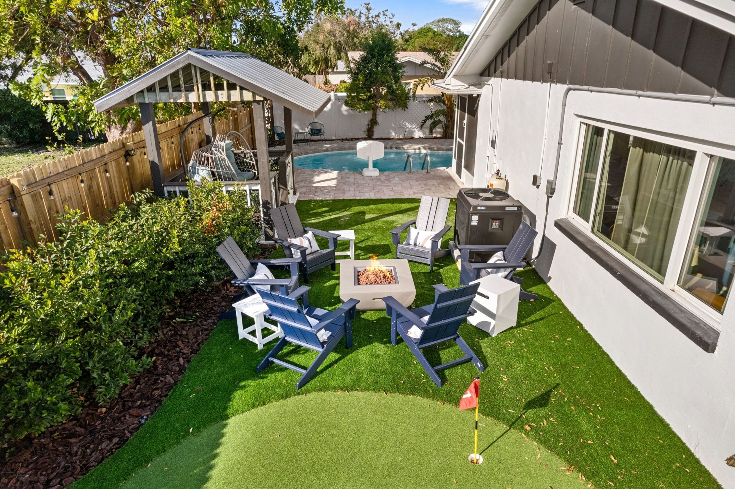 Un jardin avec une piscine, un espace salon extérieur et une terrasse.