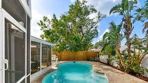 A backyard with a swimming pool, a wooden fence, and tropical plants. - 4 Br Haven Pool Hot Tub Arcade Fire Pit Putt Putt (Largo)