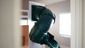 A room with a large, dark-colored, curved object mounted on the wall, a white door, and a window with a view. - 1 Mile to Honeymoon Island Pool Putt Putt (Palm Harbor)