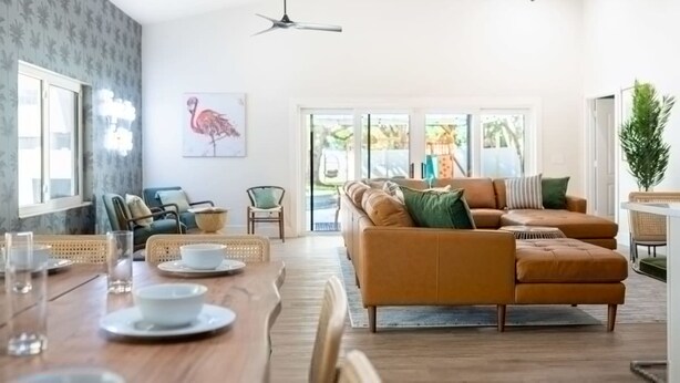A spacious living area with a large sofa, a dining table with chairs, and a ceiling fan. - 1 Mile to Honeymoon Island Pool Putt Putt (Palm Harbor)