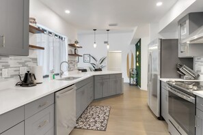 A modern kitchen with grey cabinetry, a white countertop, and stainless steel appliances. - High Tide - 3 Br Sleeps 6 - Private Pool - Games (Naples)