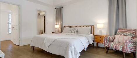 A bedroom with a bed, bedside table, chair, and a ceiling fan.