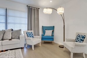 A modern living room with a white sofa set, a blue armchair, and a floor lamp. - High Tide - 3 Br Sleeps 6 - Private Pool - Games (Naples)