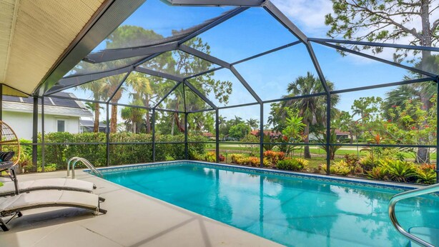 A covered outdoor swimming pool with a view of a residential area and palm trees. - High Tide - 3 Br Sleeps 6 - Private Pool - Games (Naples)
