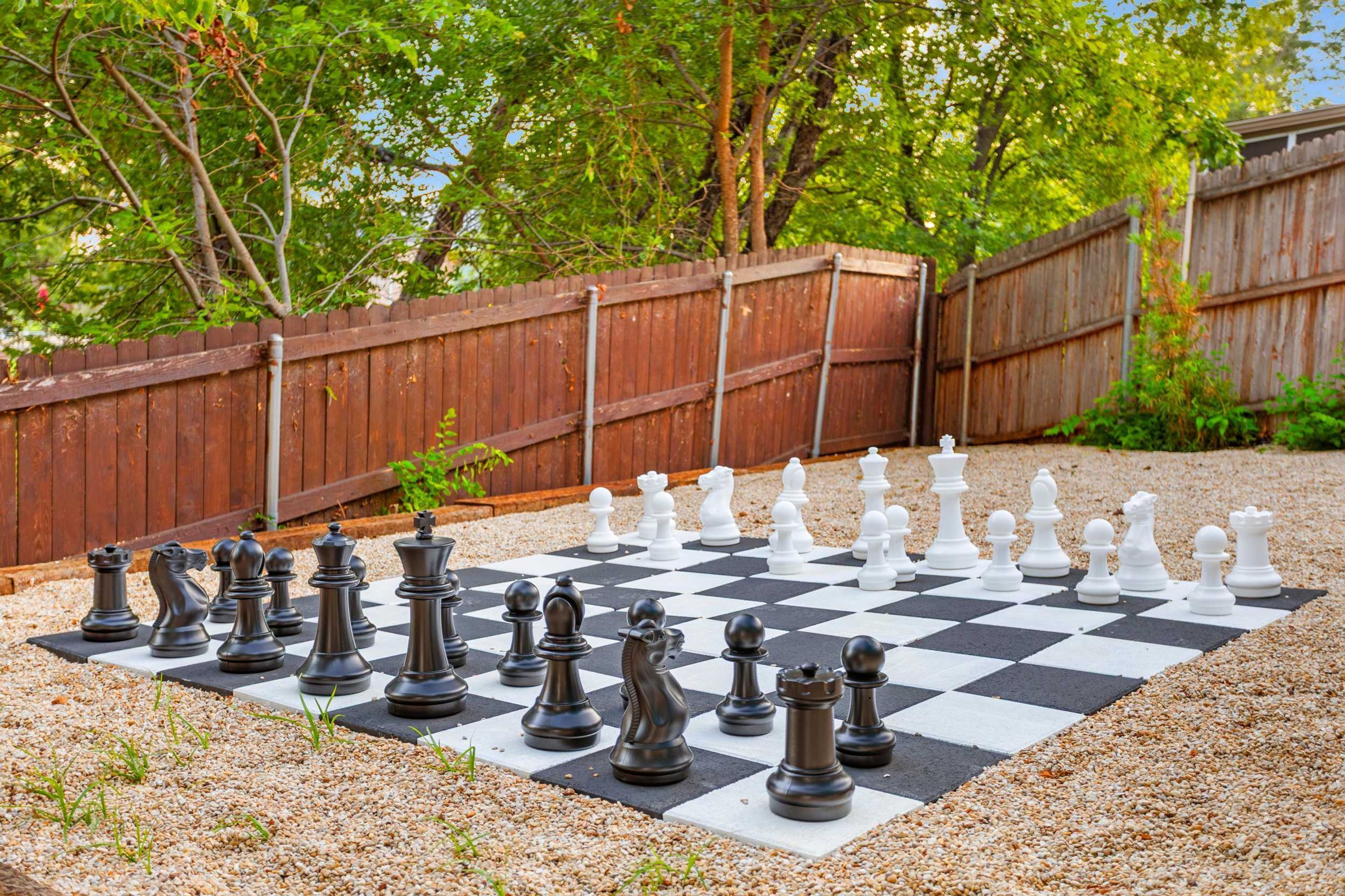 A chessboard set outdoors with a wooden fence in the background.