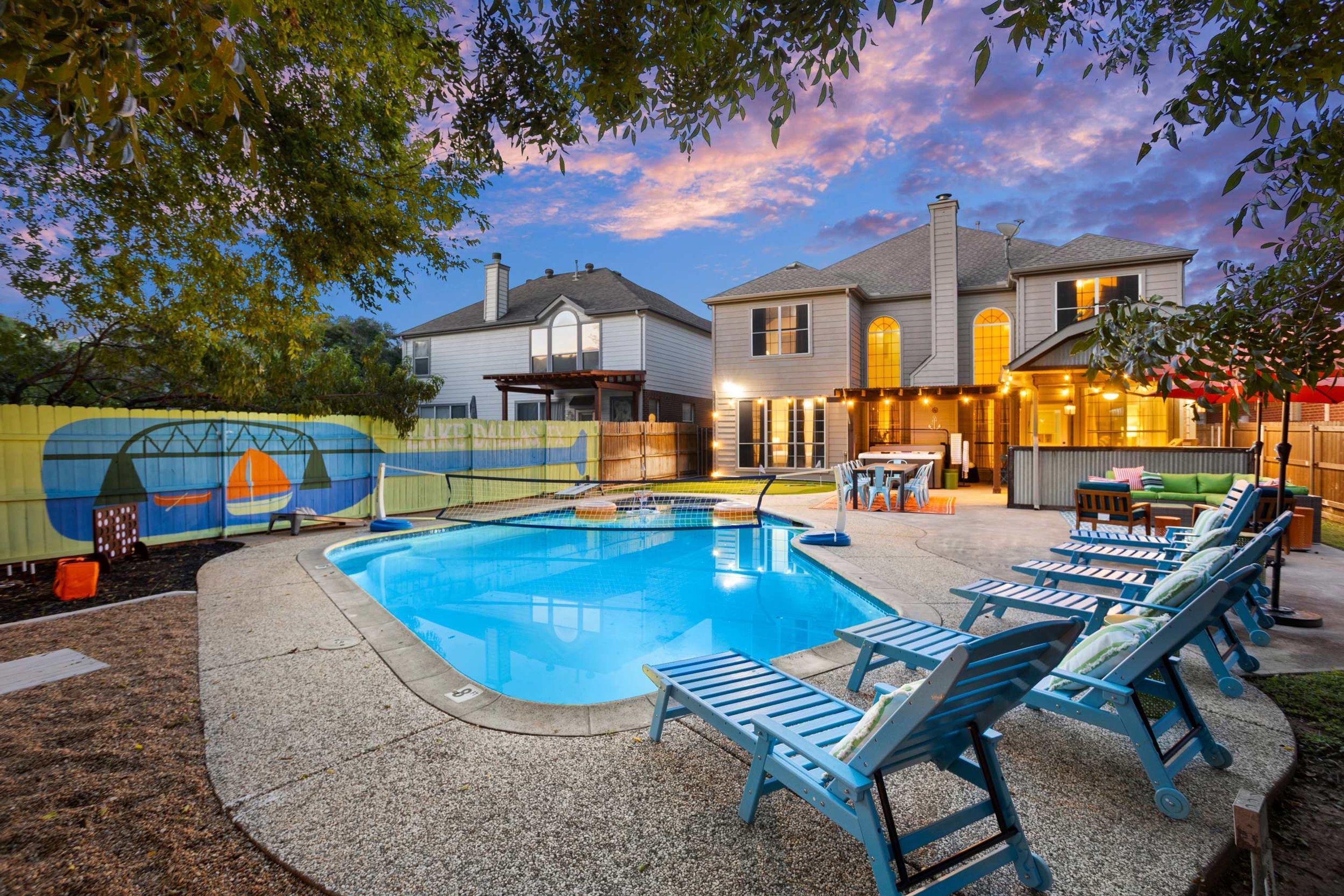 A backyard with a swimming pool, lounge chairs, and a patio area.