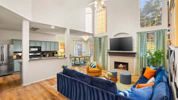 A spacious living area with a large dark blue sofa, a fireplace, and a television.