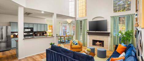 A spacious living area with a large dark blue sofa, a fireplace, and a television.