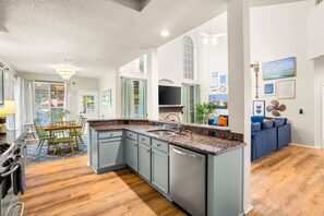 Eine moderne Küche mit Granit Arbeitsplatten, einem Geschirrspüler und einem Essbereich mit Tisch und Stühlen.