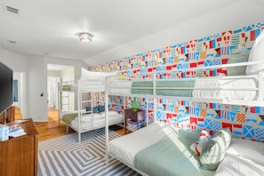 A bunk bed room with a geometric patterned wall, a television, and a wooden floor. - The Painted Paddle Pool Hottub Pickleball Court (Lake Dallas)