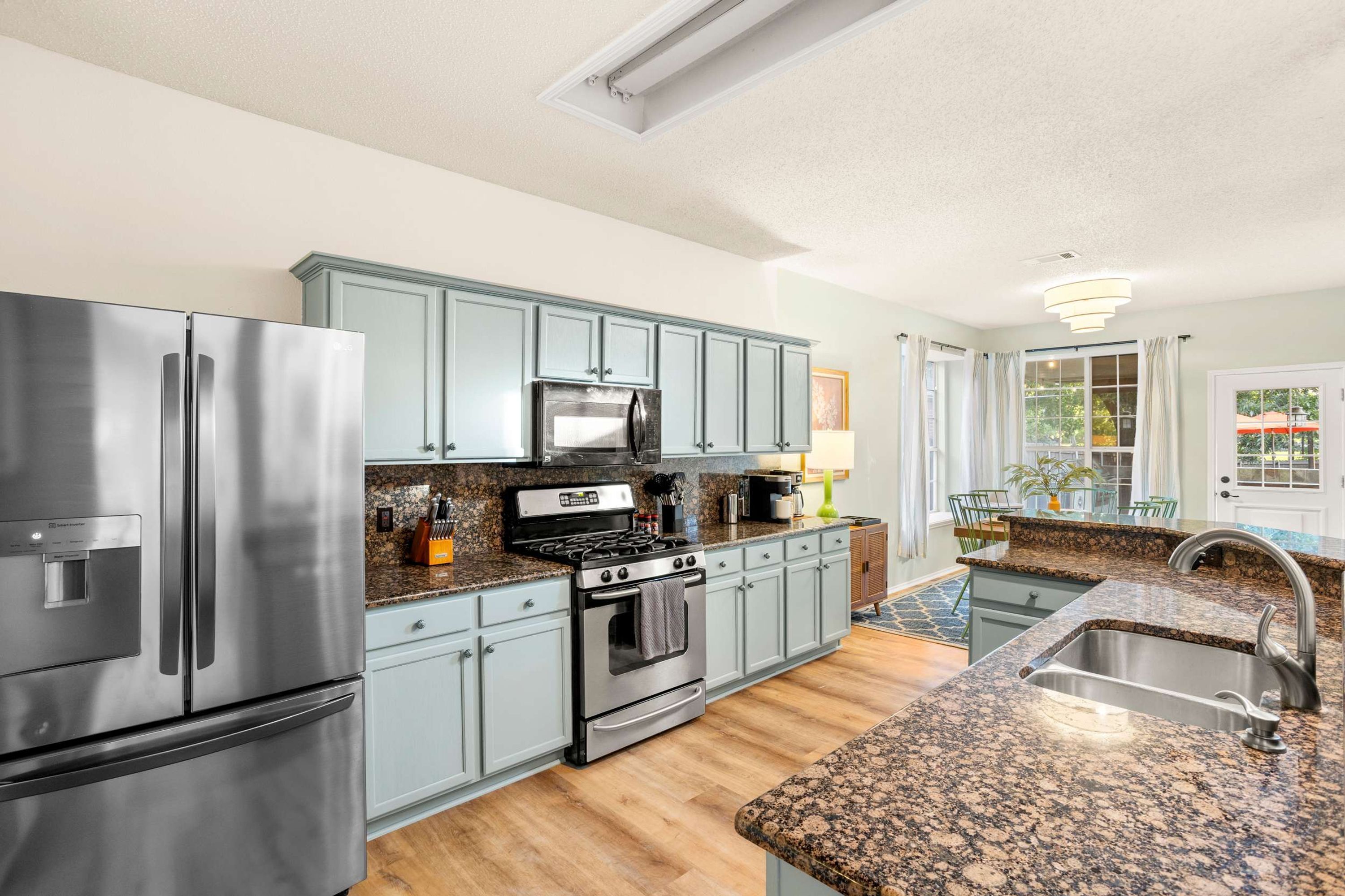 A modern kitchen with stainless steel appliances, granite countertops, and light blue cabinetry.