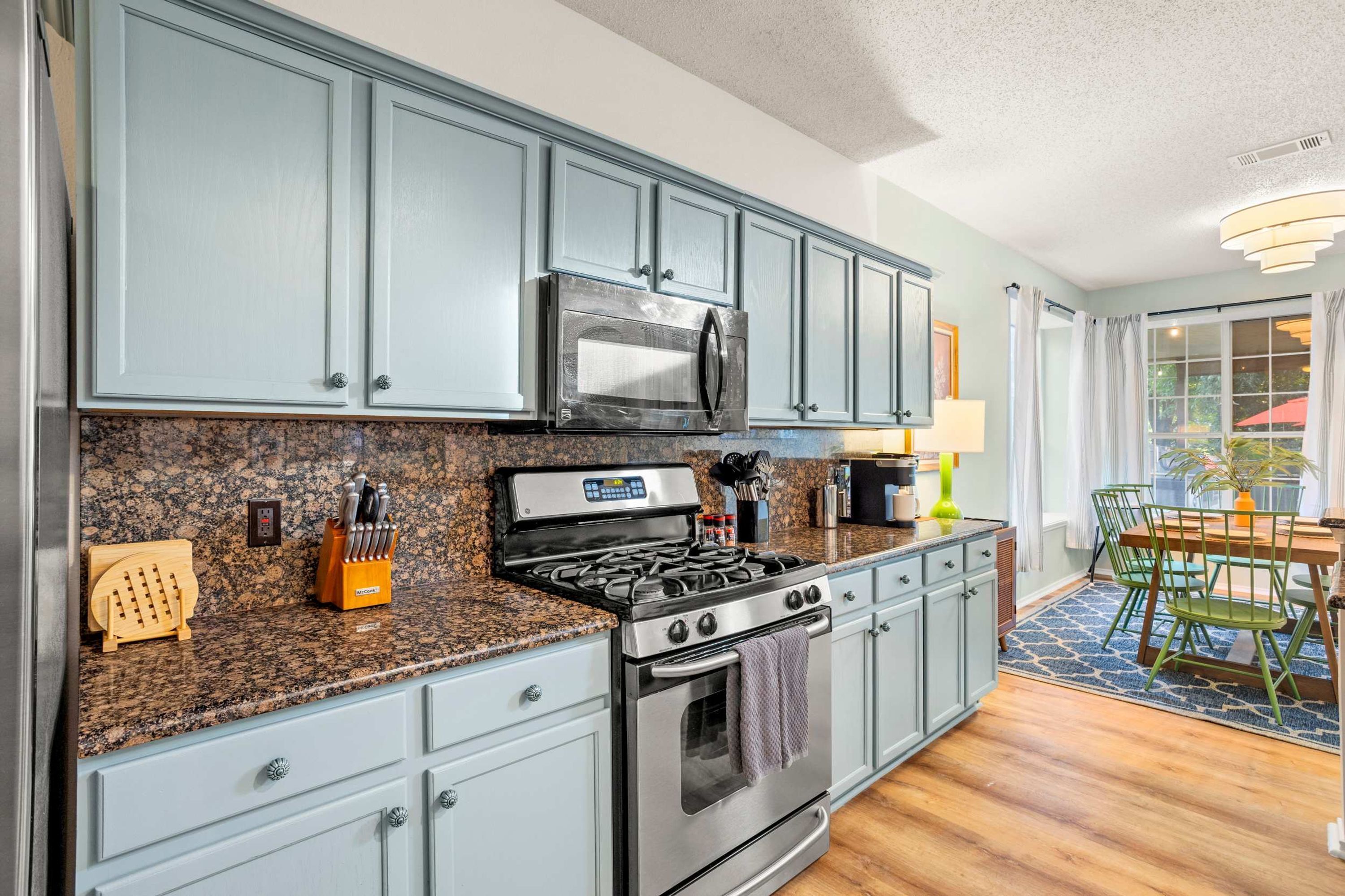 A kitchen with granite countertops, stainless steel appliances, and light gray cabinetry.