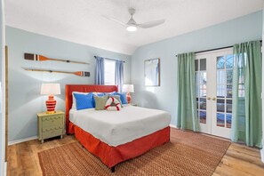 A bedroom with a bed, two nightstands, a ceiling fan, a window with curtains, and a door with a view. - The Painted Paddle Pool Hottub Pickleball Court (Lake Dallas)