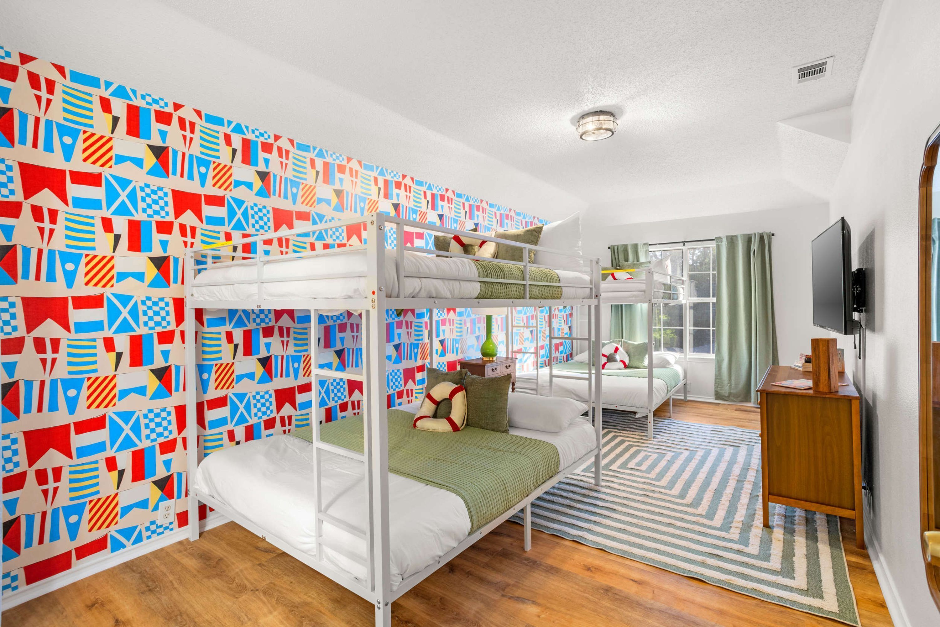Una habitación con literas, televisión y un papel tapiz estampado.