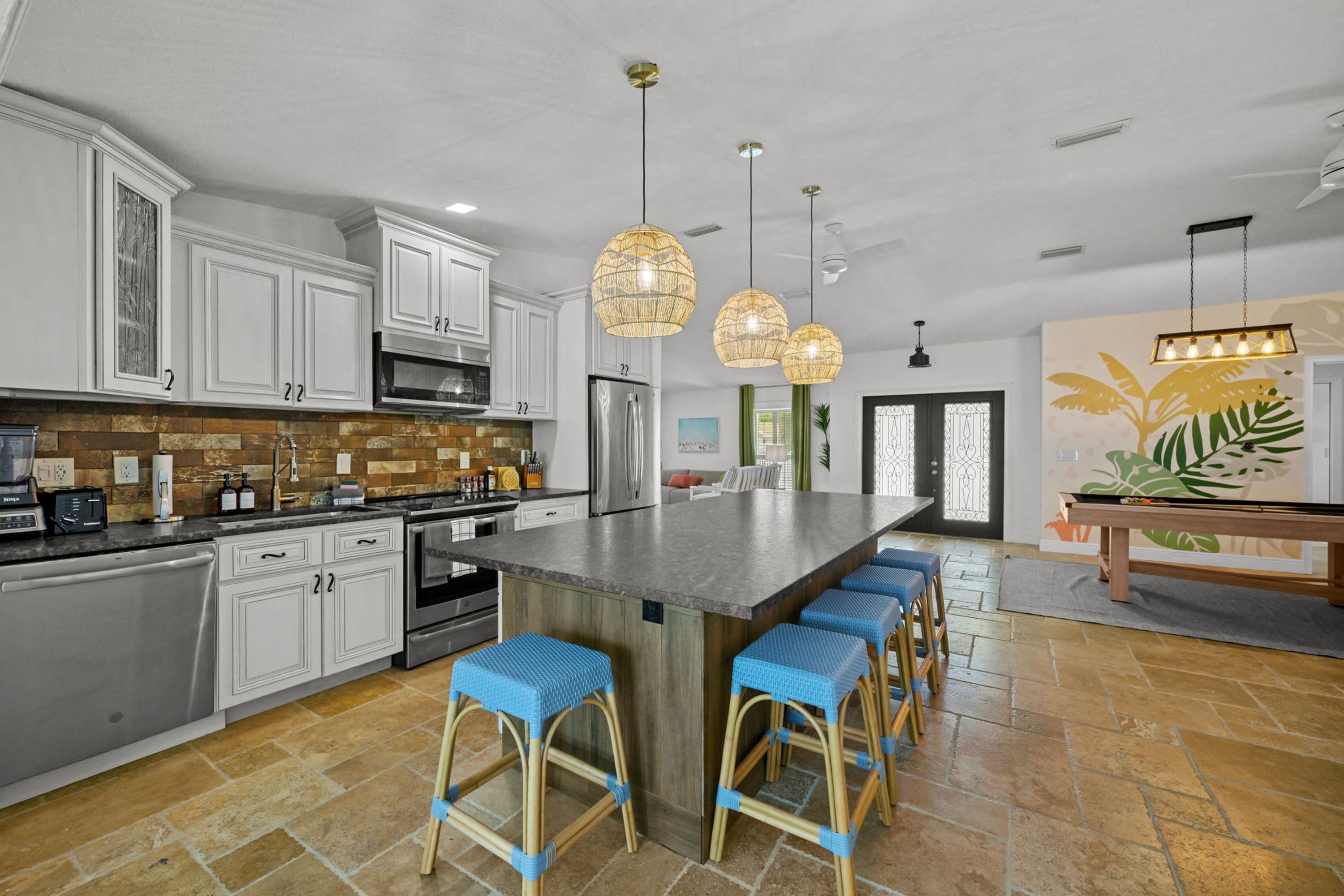 Una cocina moderna con armarios blancos, una isla grande con taburetes de bar e iluminación colgante.