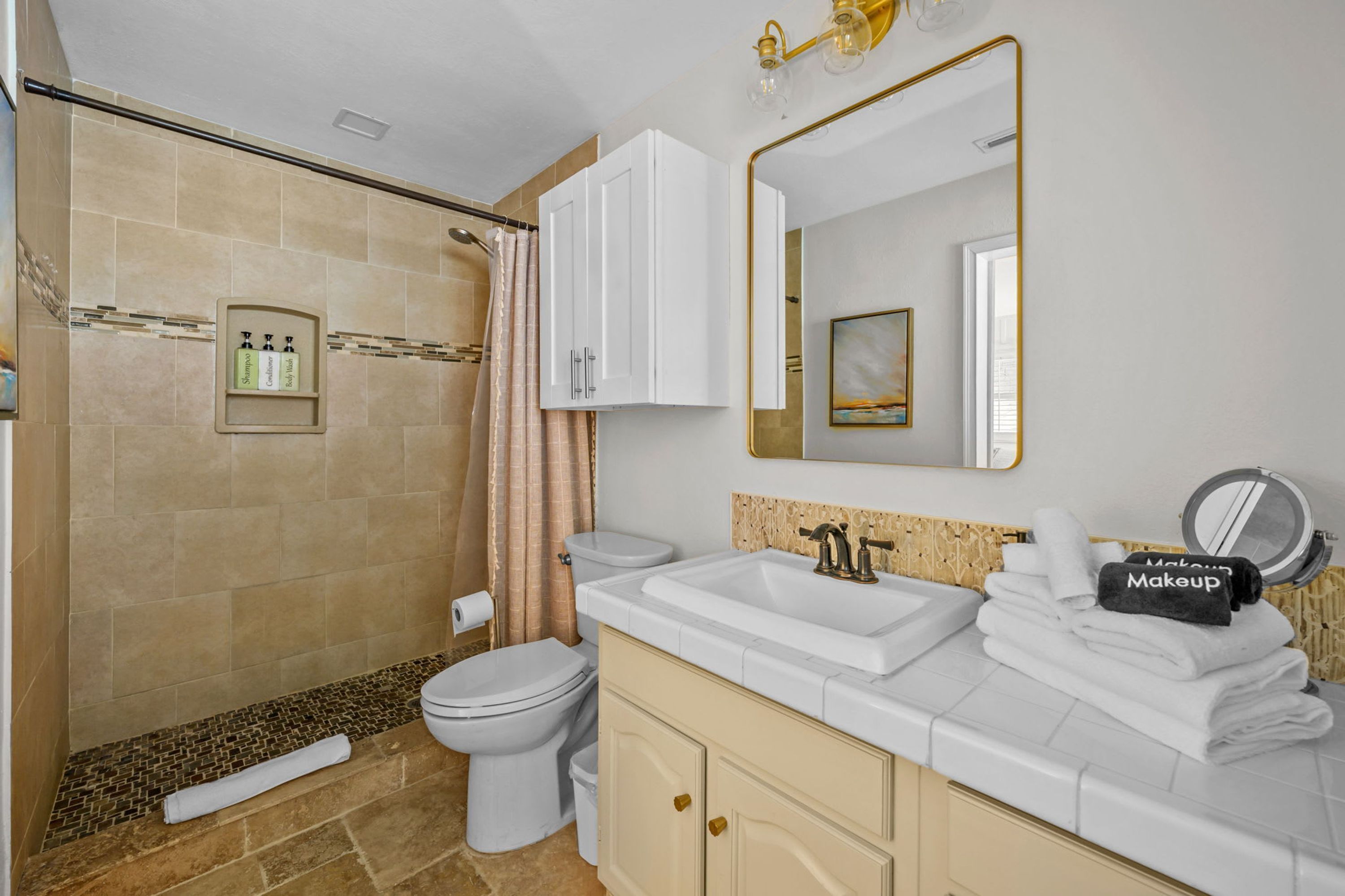 A bathroom with a shower, toilet, sink, and vanity.