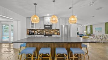 A spacious kitchen with a central island, bar stools, and pendant lighting.