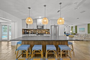 Uma cozinha ampla com ilha central, banquetas e iluminação pendente.