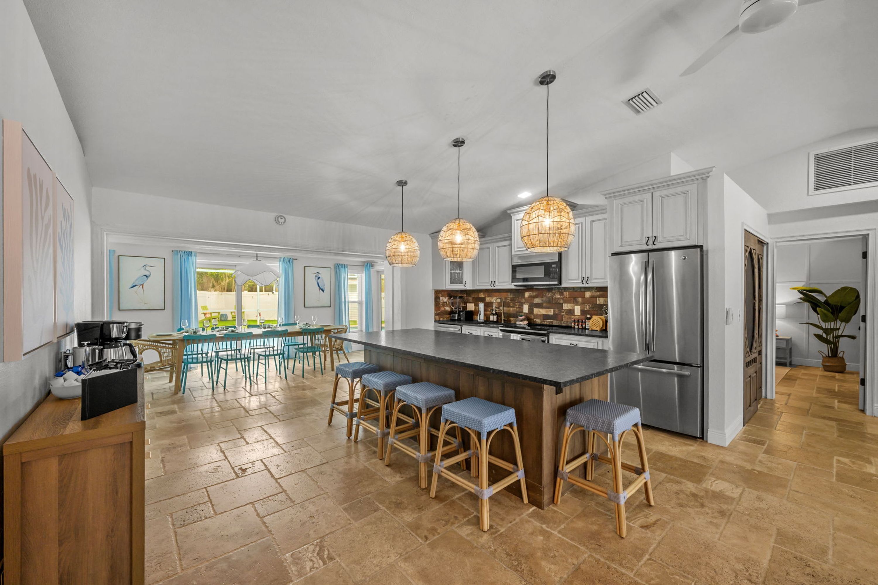 A spacious kitchen with a central island, bar stools, and pendant lighting.