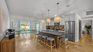 A spacious kitchen with a central island, bar stools, and pendant lighting.
