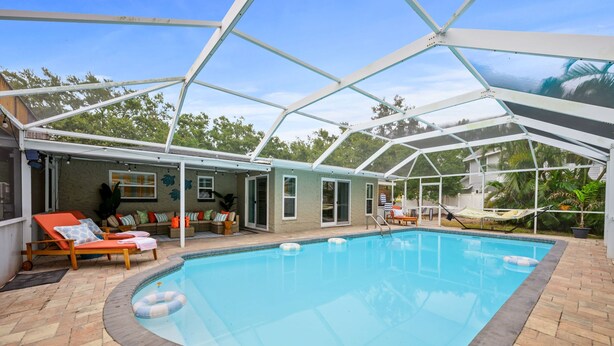 A covered swimming pool with lounge chairs and a patio area. - 7-bedrooms Sports Court Pool Putt Putt (Seminole)