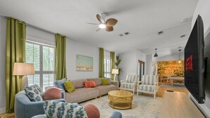 A living room with a sofa, armchairs, a coffee table, and a television. - 7-bedrooms Sports Court Pool Putt Putt (Seminole)