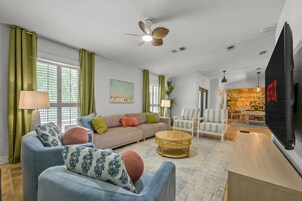 Una sala de estar con sofá, sillones, una mesa de centro y televisor.