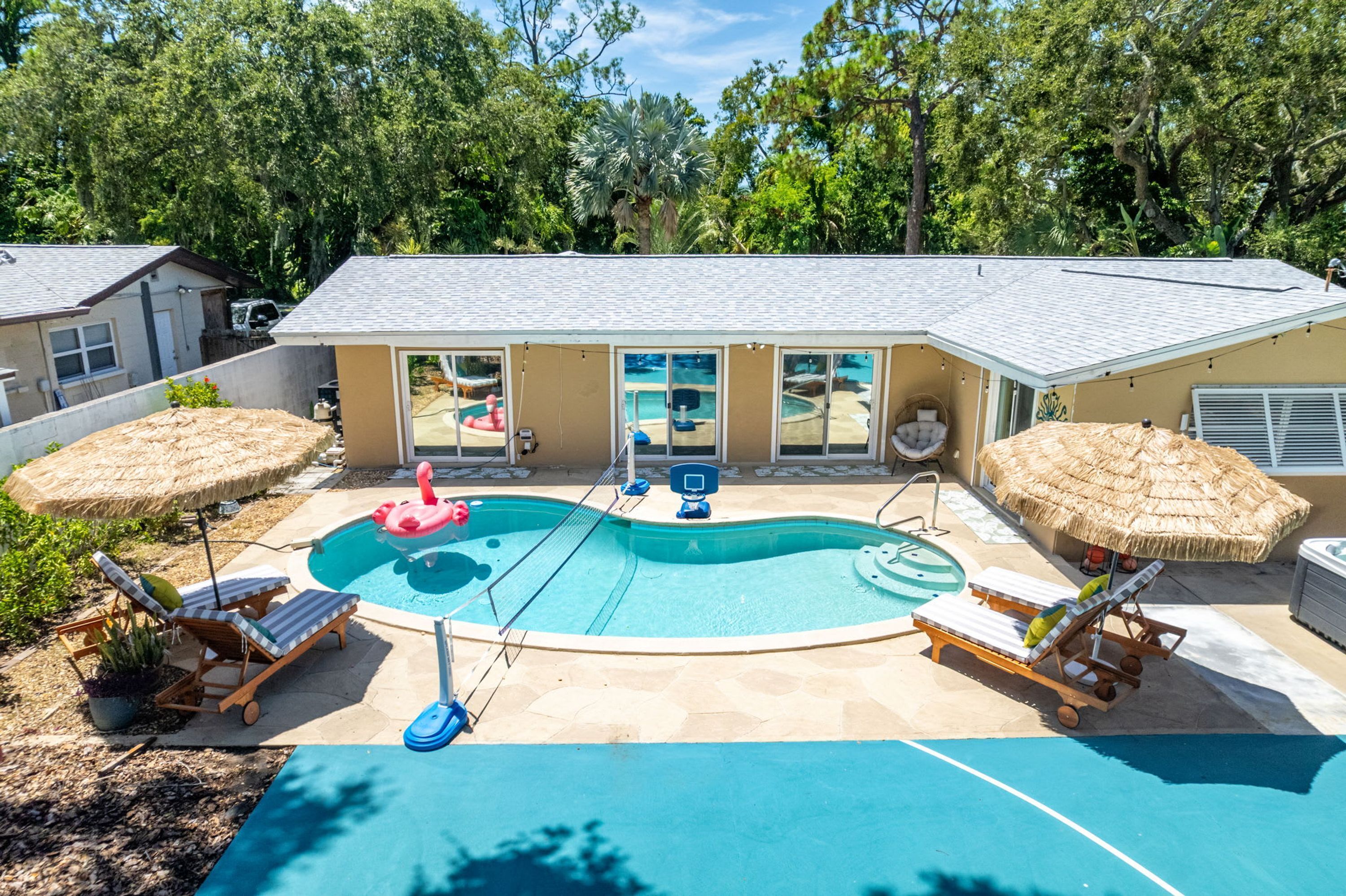 A backyard with a swimming pool, lounge chairs, and a hot tub.