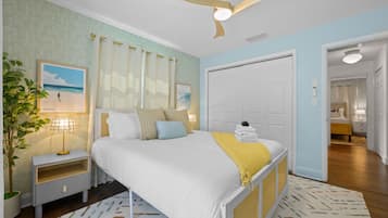 A bedroom with a bed, nightstands, a ceiling fan, and a door leading to another room.