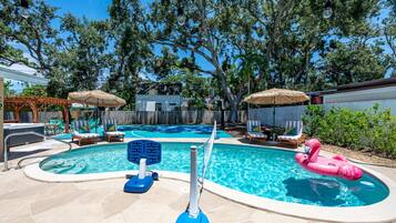 A swimming pool with a hot tub, lounge chairs, and a flamingo float.