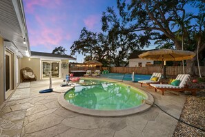 Ein Garten mit Swimmingpool, Liegestühlen und Whirlpool.