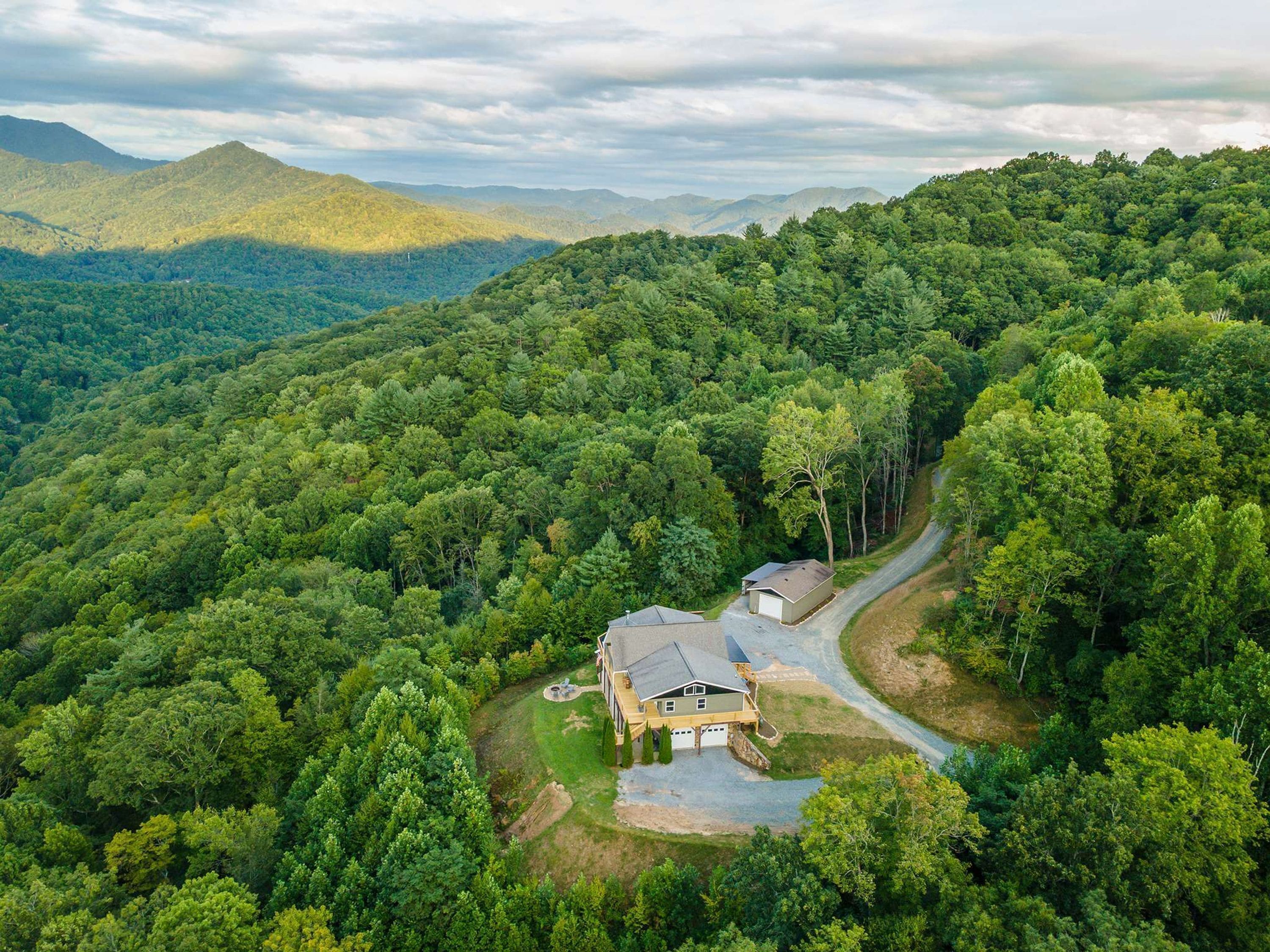 A house surrounded by dense forest with a winding driveway.