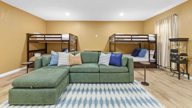A room with bunk beds, a green sofa, and a small table. - Pool Fire Pit Retreat Sleeps 14 - BBQ Grill (Largo)